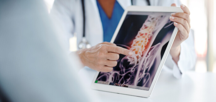 spinal cord diagram on a tablet, doctor pointing to a problem area