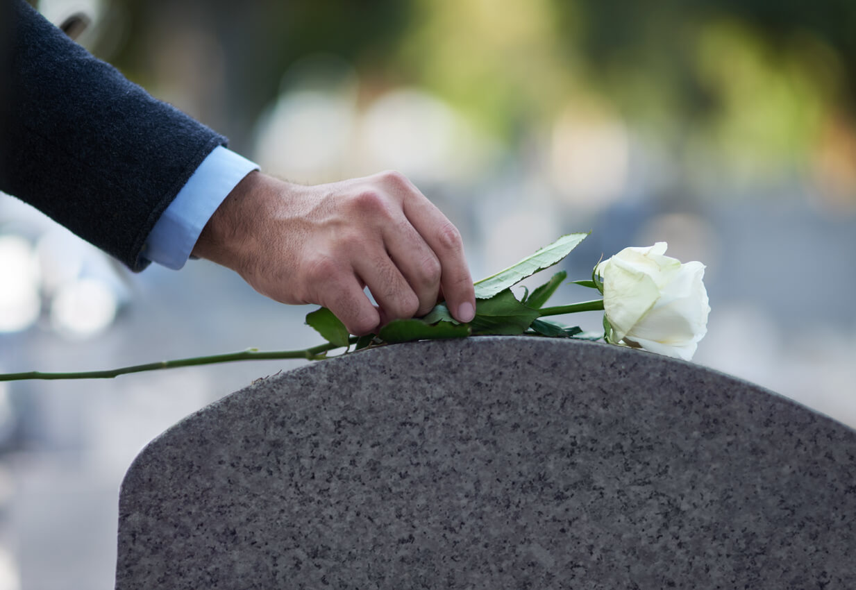 man laying flower on grave